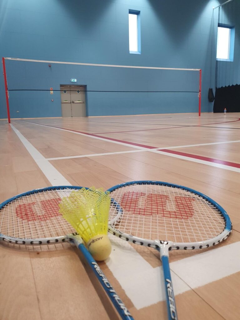 a picture of two badminton rackets and a shuttlecock on the court