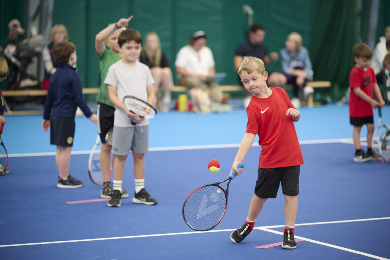 an action shot of a young boy about to hit a tennis ball with his racket